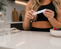 lady holding her peptide queens pen standing at a kitchen bench